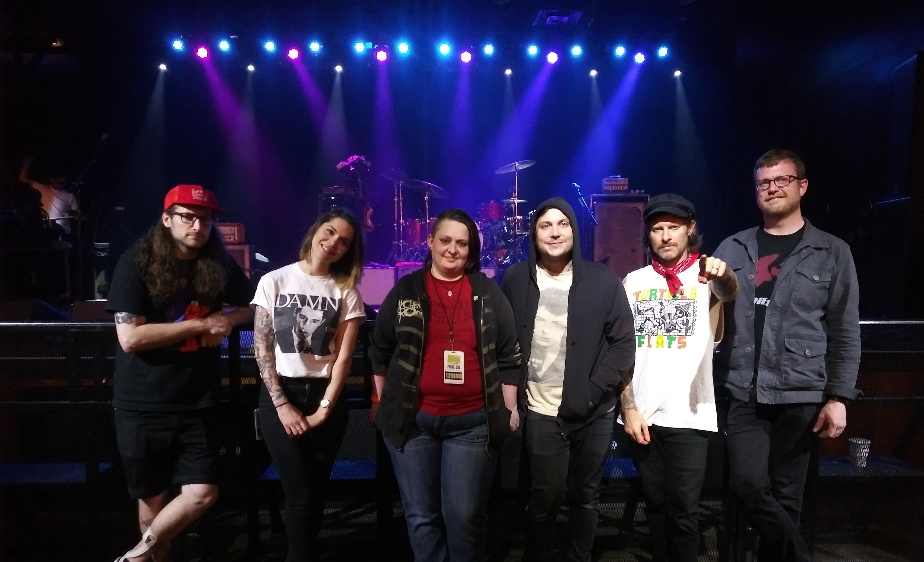 A fan taking a photo with a band in front of the stage